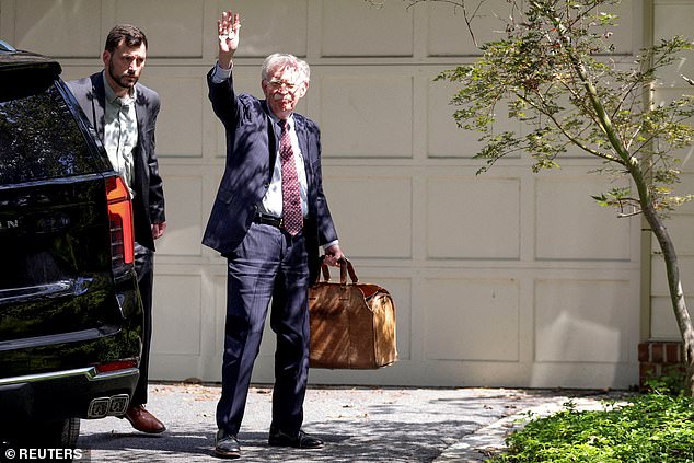 Bolton waves to the press on the day his house was raided by FBI agents.