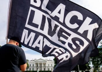 A man carries a Black Lives Matter flag in Lafayette Square outside the White House in a file photo from Aug. 27, 2020.