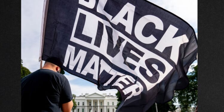 A man carries a Black Lives Matter flag in Lafayette Square outside the White House in a file photo from Aug. 27, 2020.