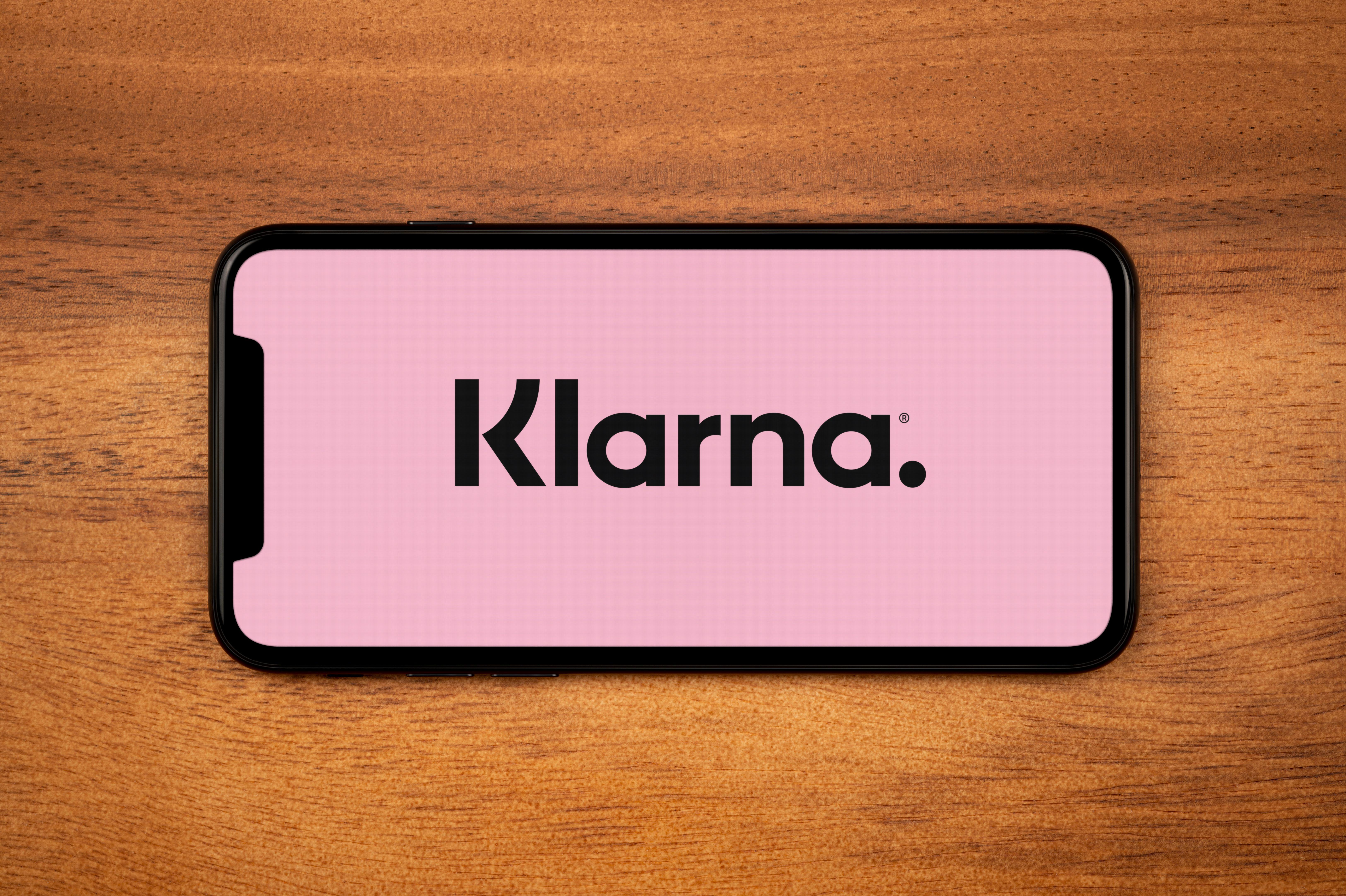 Smartphone displaying the Klarna logo on a pink background.