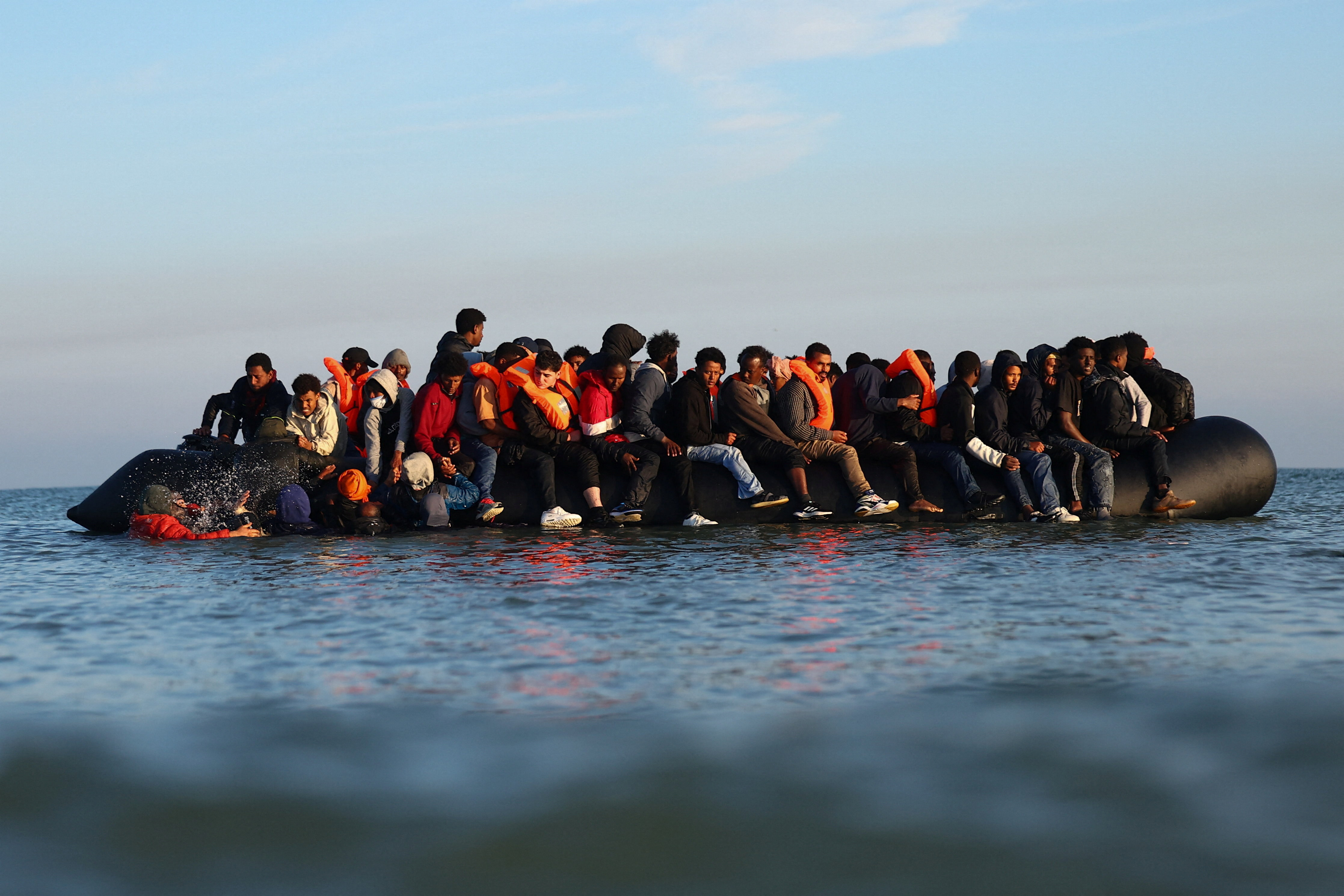 A group of migrants on an inflatable dinghy leaving the beach of Petit-Fort-Philippe.
