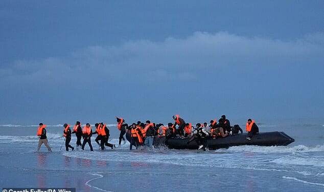 Dozens of young men run ashore from a deflating dinghy in France yesterday. More than 60,000 have now arrived in the UK since Labour won power