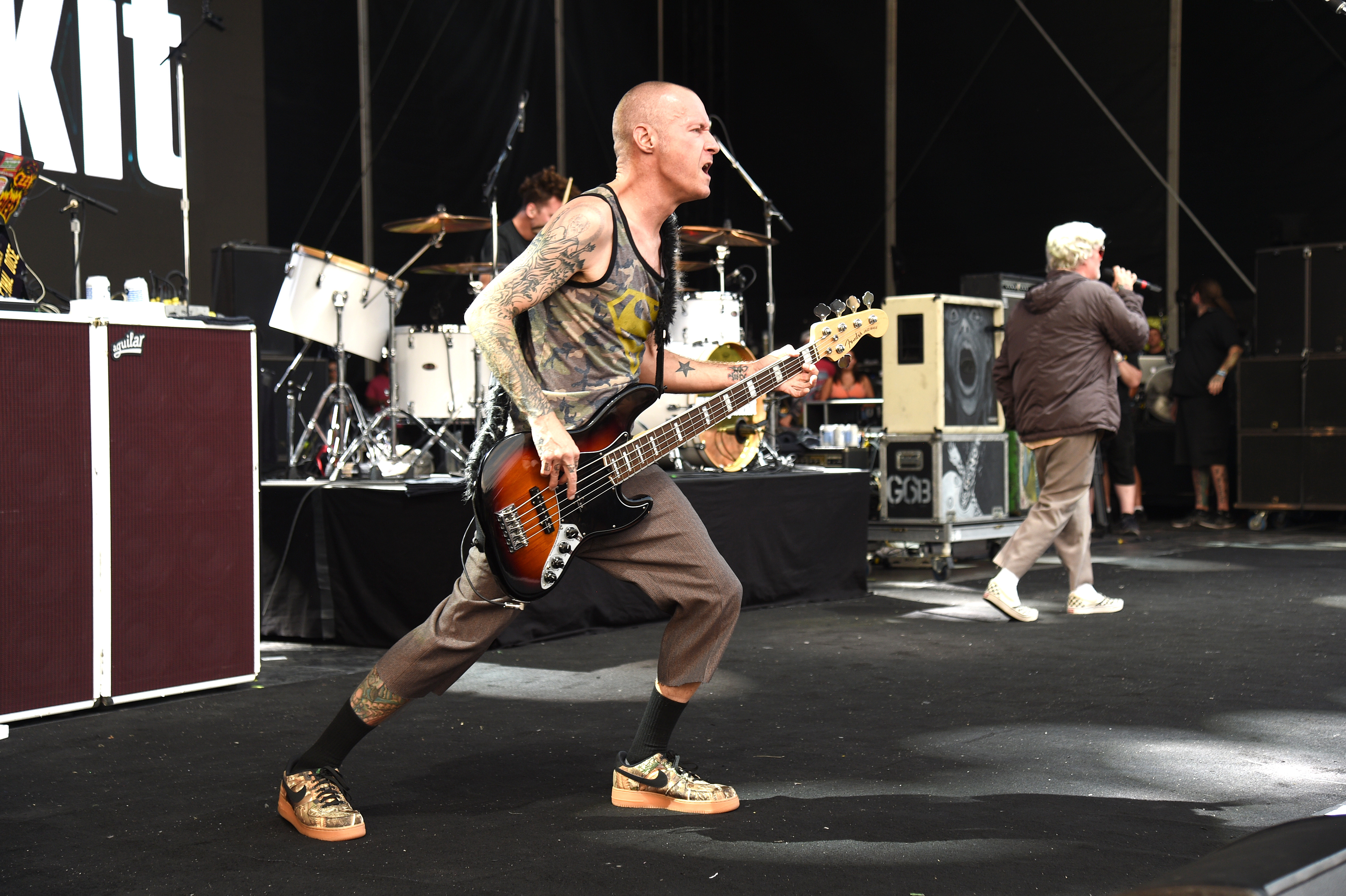 A bald man playing bass guitar on stage at a concert.