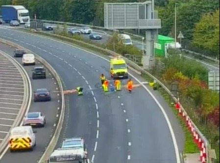 Road maintenance crew working on a highway with traffic passing by.