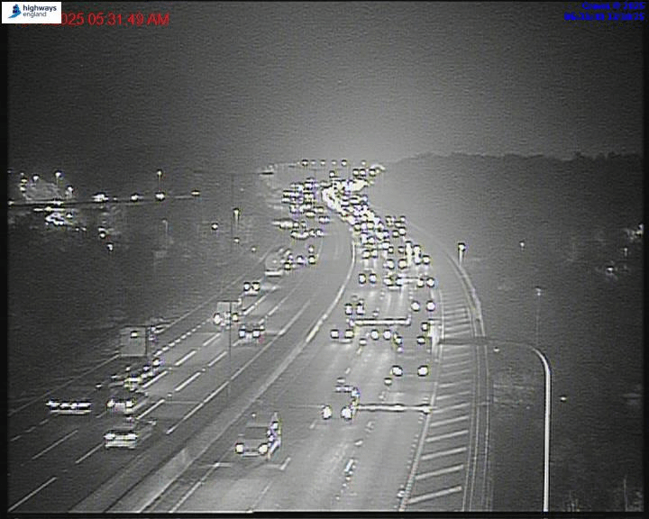 Overhead night vision view of a highway with heavy traffic.