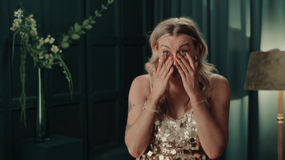 A woman with blonde hair in a sparkly dress cries with her hands covering her face.