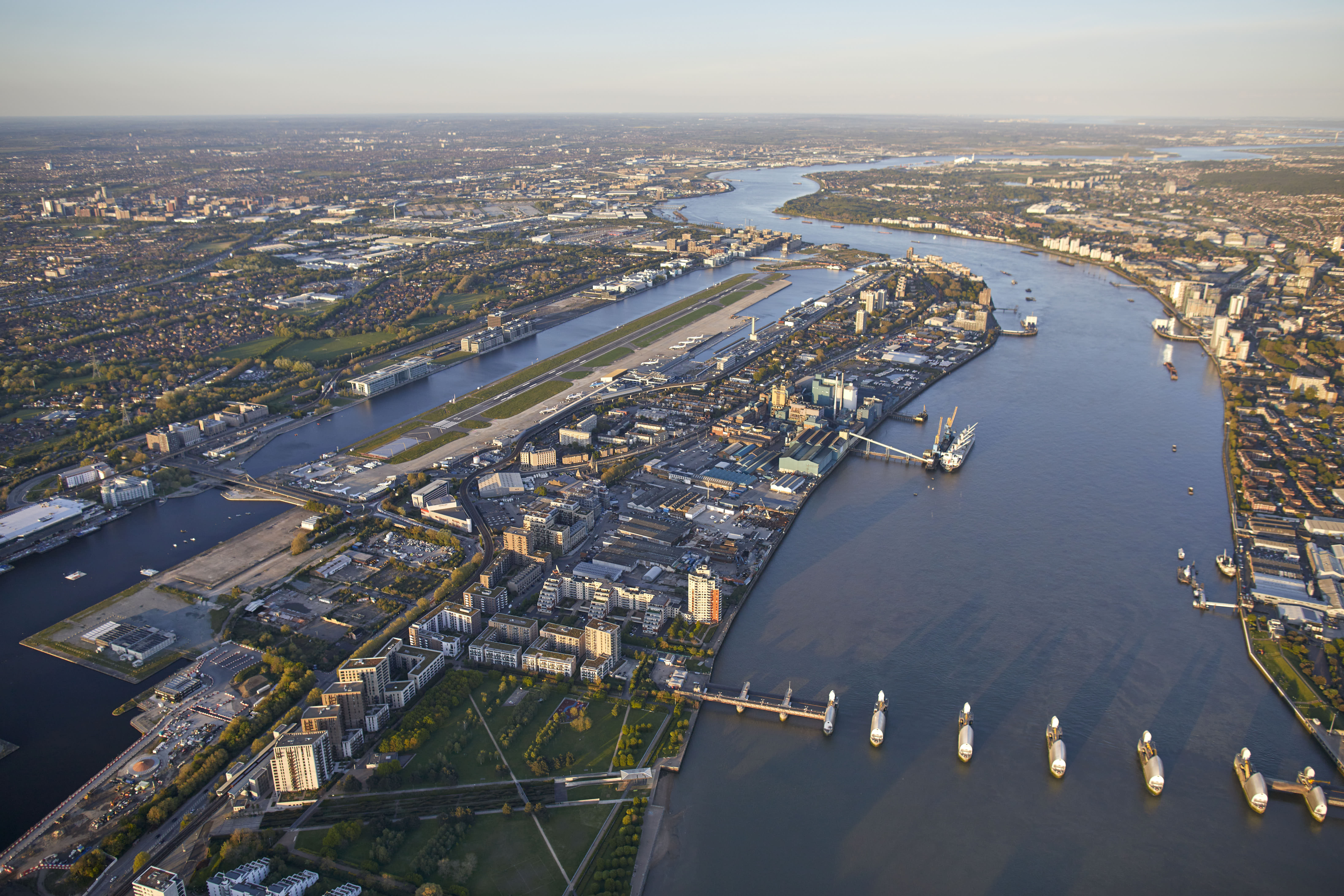 Aerial view of London City Airport with its runway, buildings, and the Thames River.
