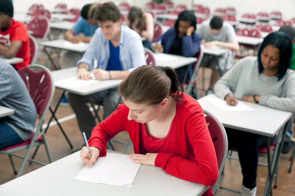 Young woman in a red shirt taking an exam in an exam hall.