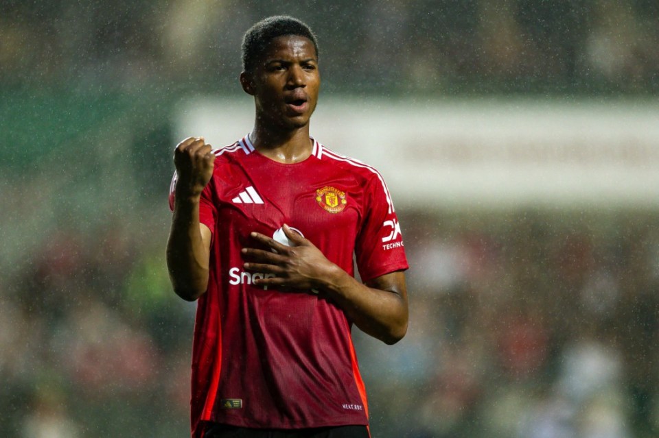 A soccer player in a red jersey with a hand on his chest and a raised fist.