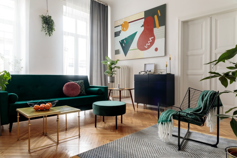 Living room with a green velvet sofa, mid-century modern furniture, and abstract art.