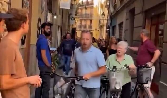 A group of tourists walk away after a tense confrontation with Spanish locals almost led to a brawl