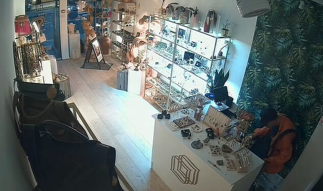 A brazen thief who broke into a luxury boutique can be seen rifling through the cash register during a daring early morning robbery