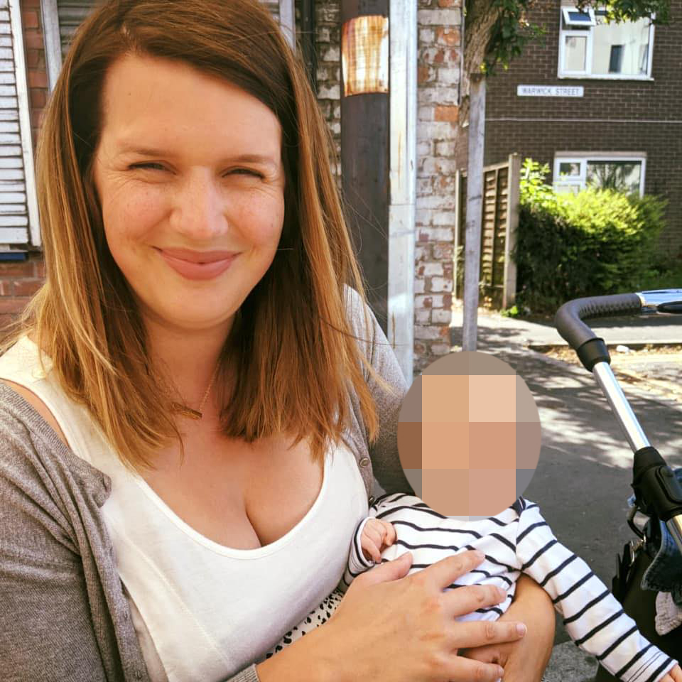Jennifer Cahill holding a baby in front of a street sign for Warwick Street.