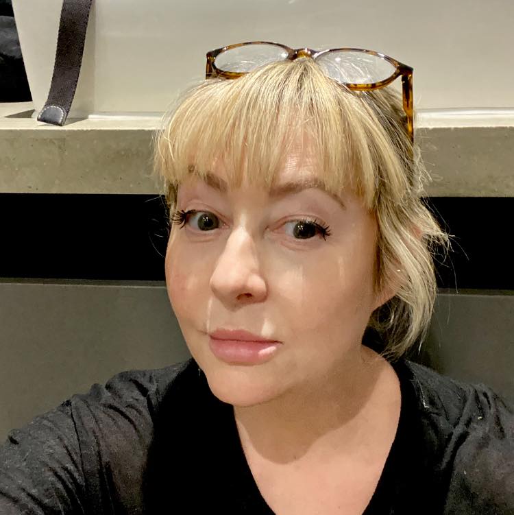 Sam Wall looking at the camera with glasses on top of her head.