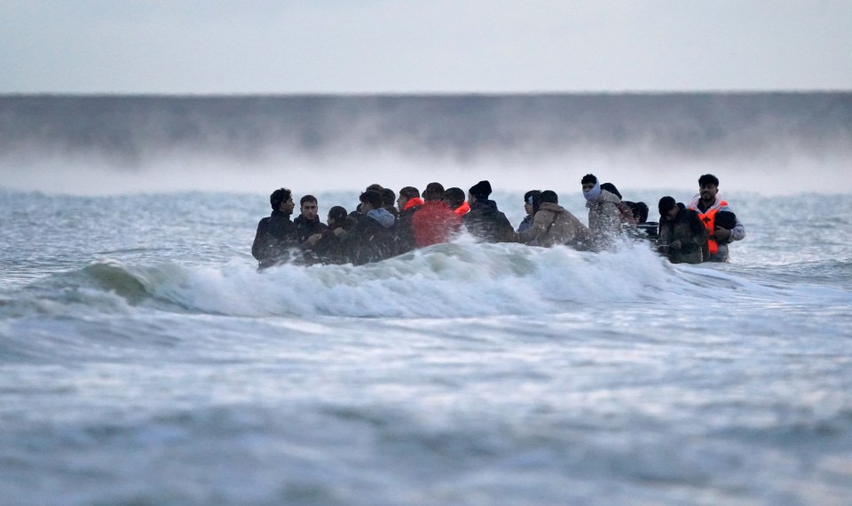 Migrants in the sea wait to board a small boat in Gravelines, France.