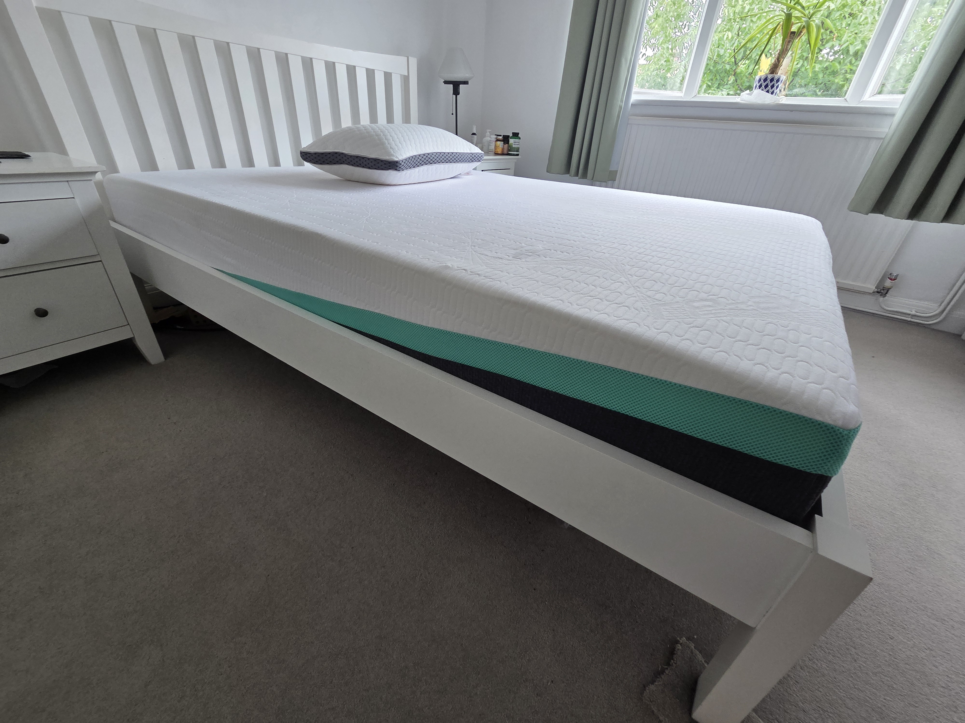 White bed frame with a teal and black mattress.
