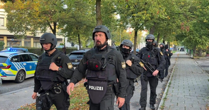 Police officers walk along a footpath after a fire in a detached house in Munich, Germany, on Wednesday.
