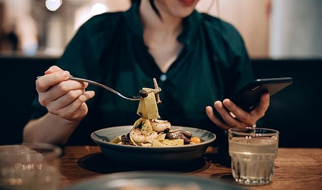 Using a mobile phone at the dinner table is considered to be a modern  bad-manner (stock image)