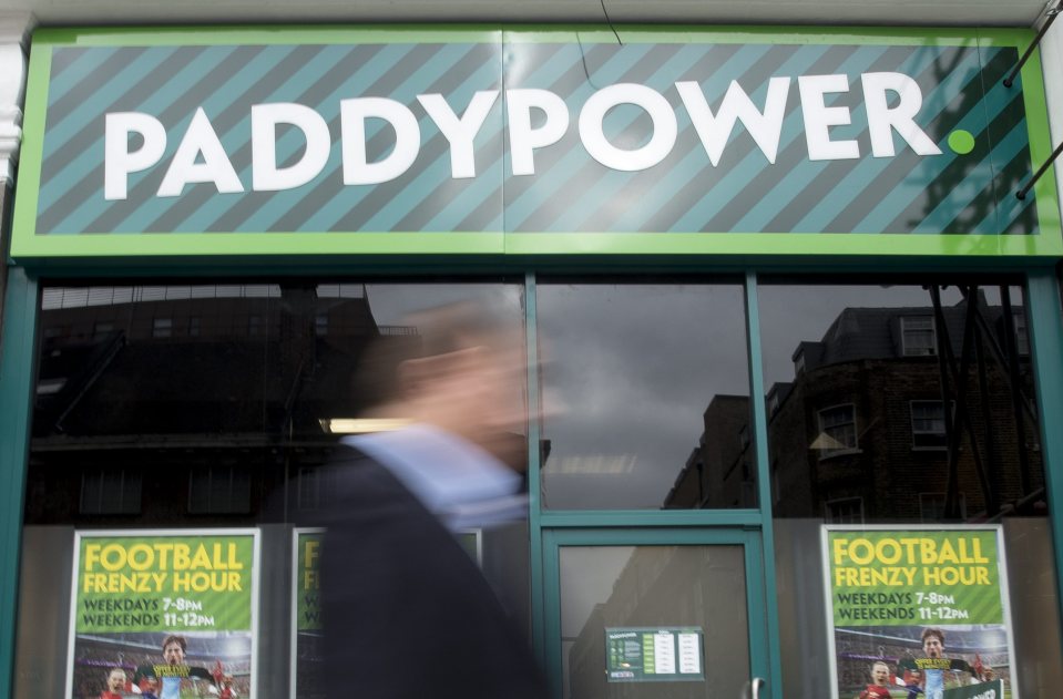 The exterior of a Paddy Power shop with a blurred person walking past.
