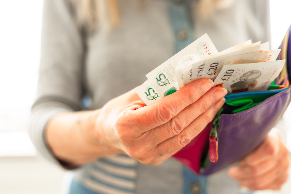 Close-up of a senior woman's hands taking British banknotes from her wallet.