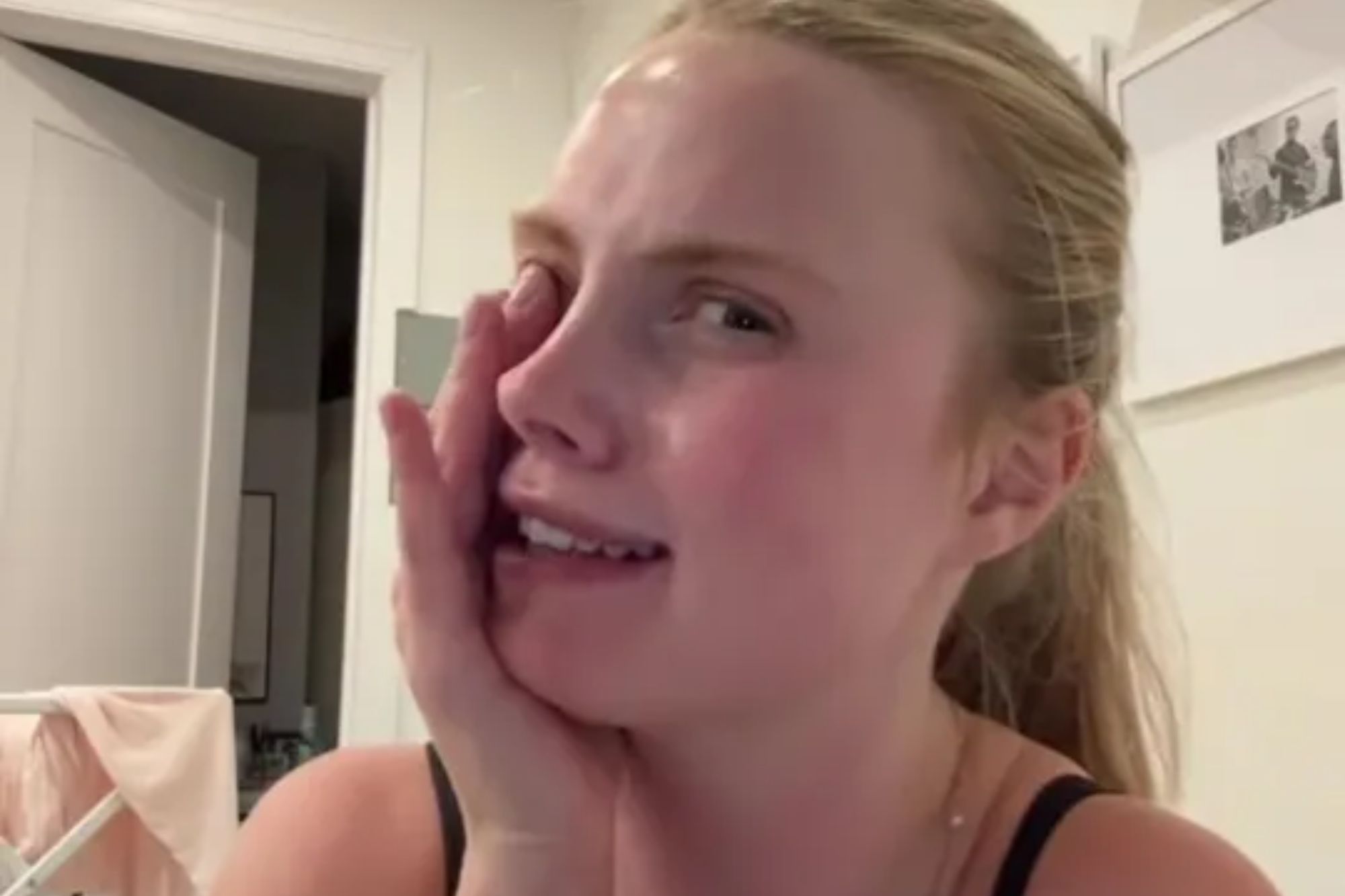 An image collage containing 1 images, Image 1 shows A person wearing a black top with their hand to their cheek