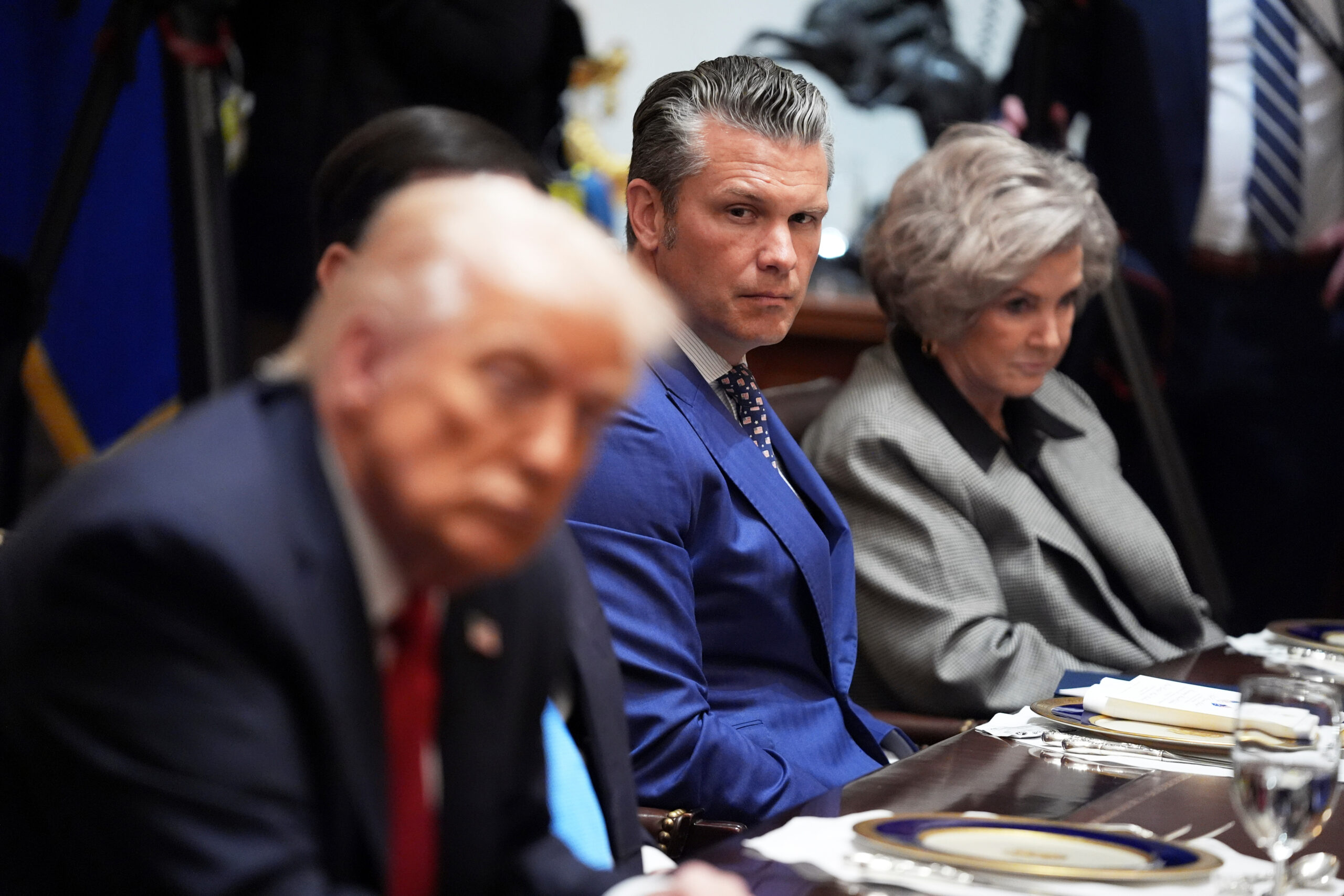 Defense Secretary Pete Hegseth listens as he and White House Chief of Staff Susie Wiles, right, listen during a meeting Monday with President Donald Trump, in foreground left, and Australian Prime Minister Anthony Albanese at the White House in Washington, D.C.