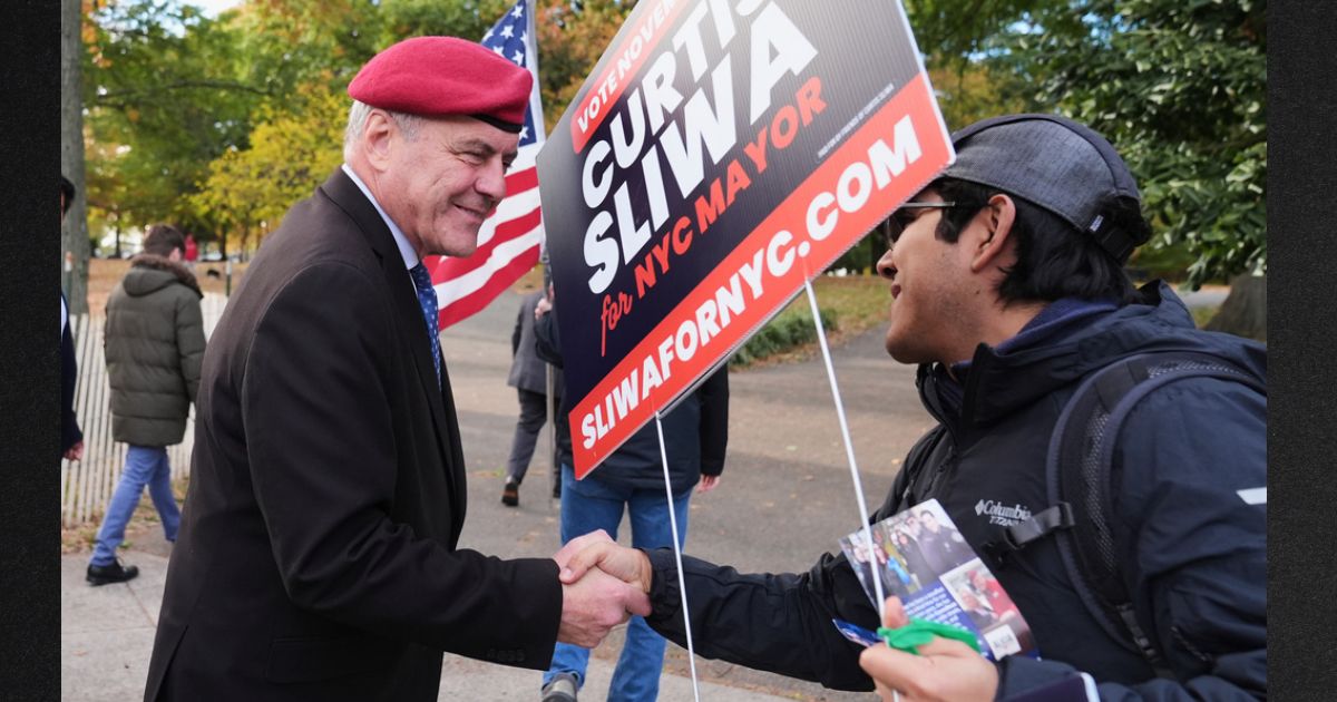 New York City mayoral candidate Curtis Sliwa, left, shakes hands with a volunteer Tuesday in the Queens borough of New York