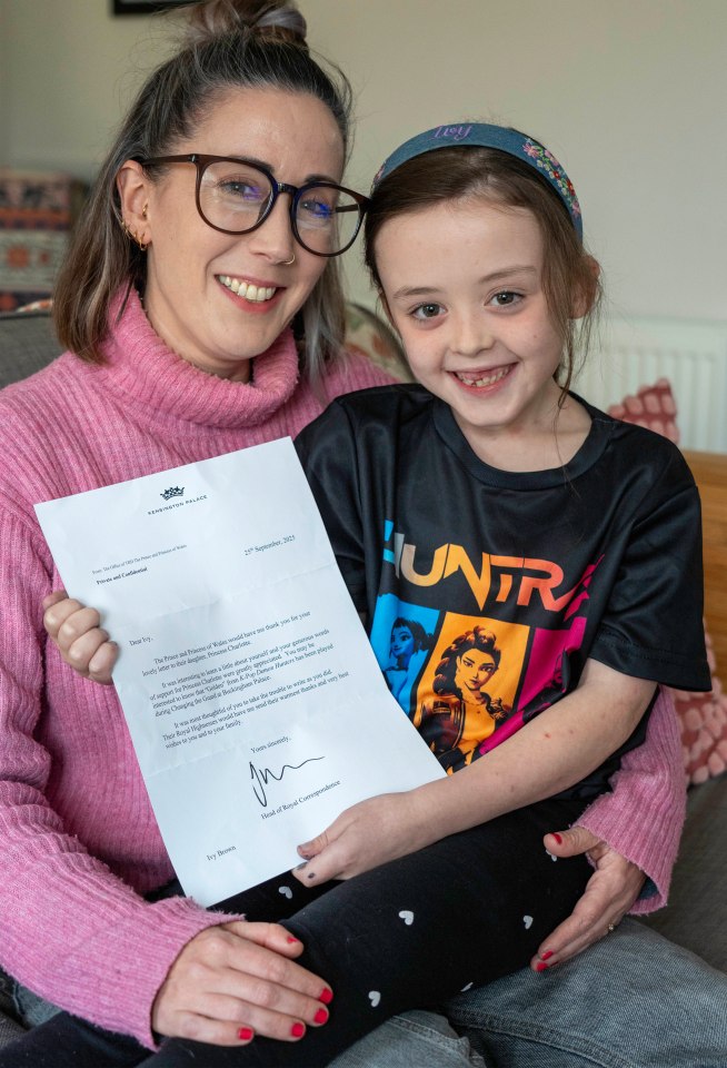Ivy Brown and her mother Louise King smiling while holding a letter from Kensington Palace.