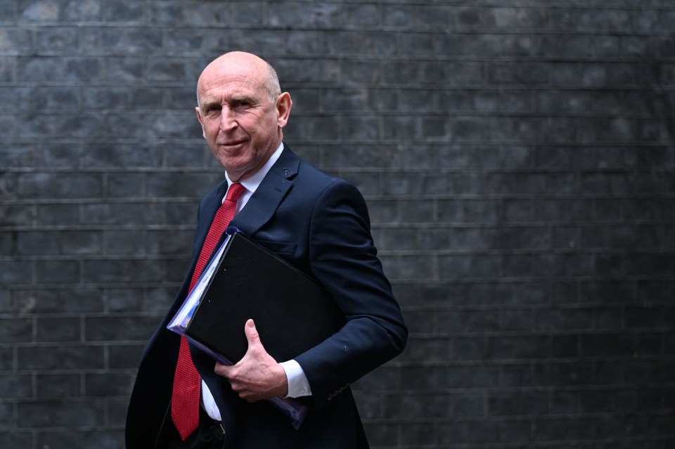 British Defense Minister John Healey walks outside, holding a binder.