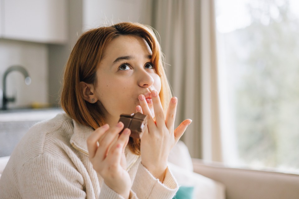 Young woman on a sofa eating chocolate.