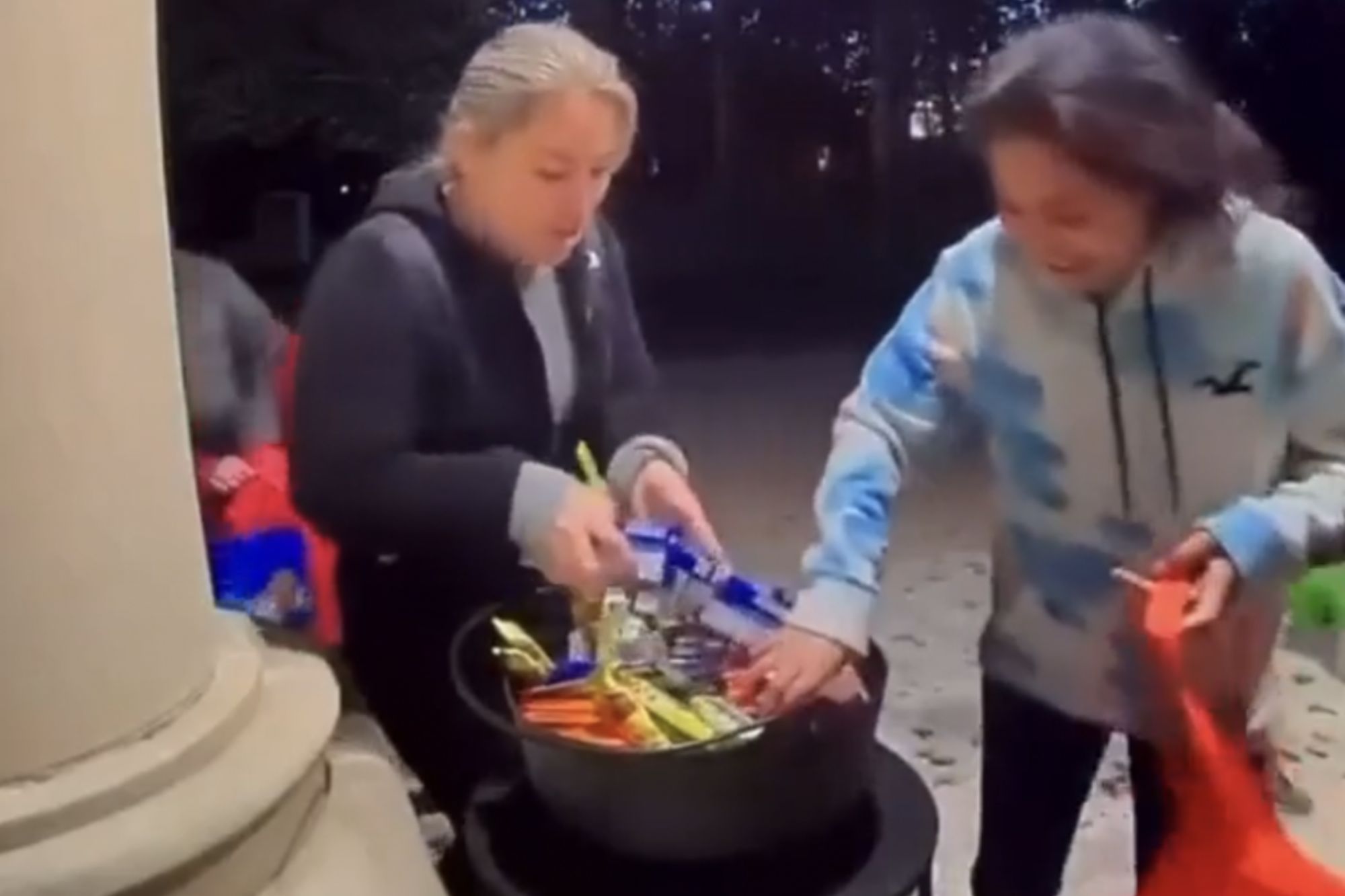 An image collage containing 1 images, Image 1 shows Two adults raiding a trick-or-treat candy bowl
