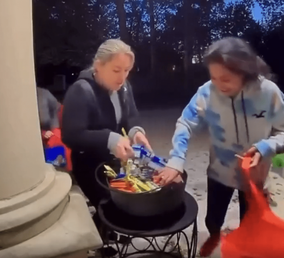 Two adults raiding a trick-or-treat candy bowl.