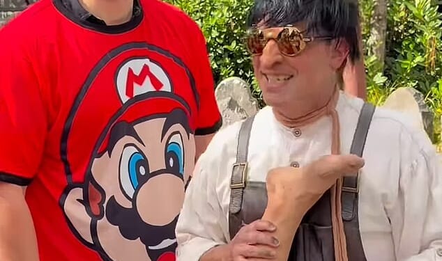 David Habour stops for a picture with a fan while wearing a red Mario T-shirt during a day out at the Epic Universe theme park in Orlando, Florida, with Lily Allen's daughters