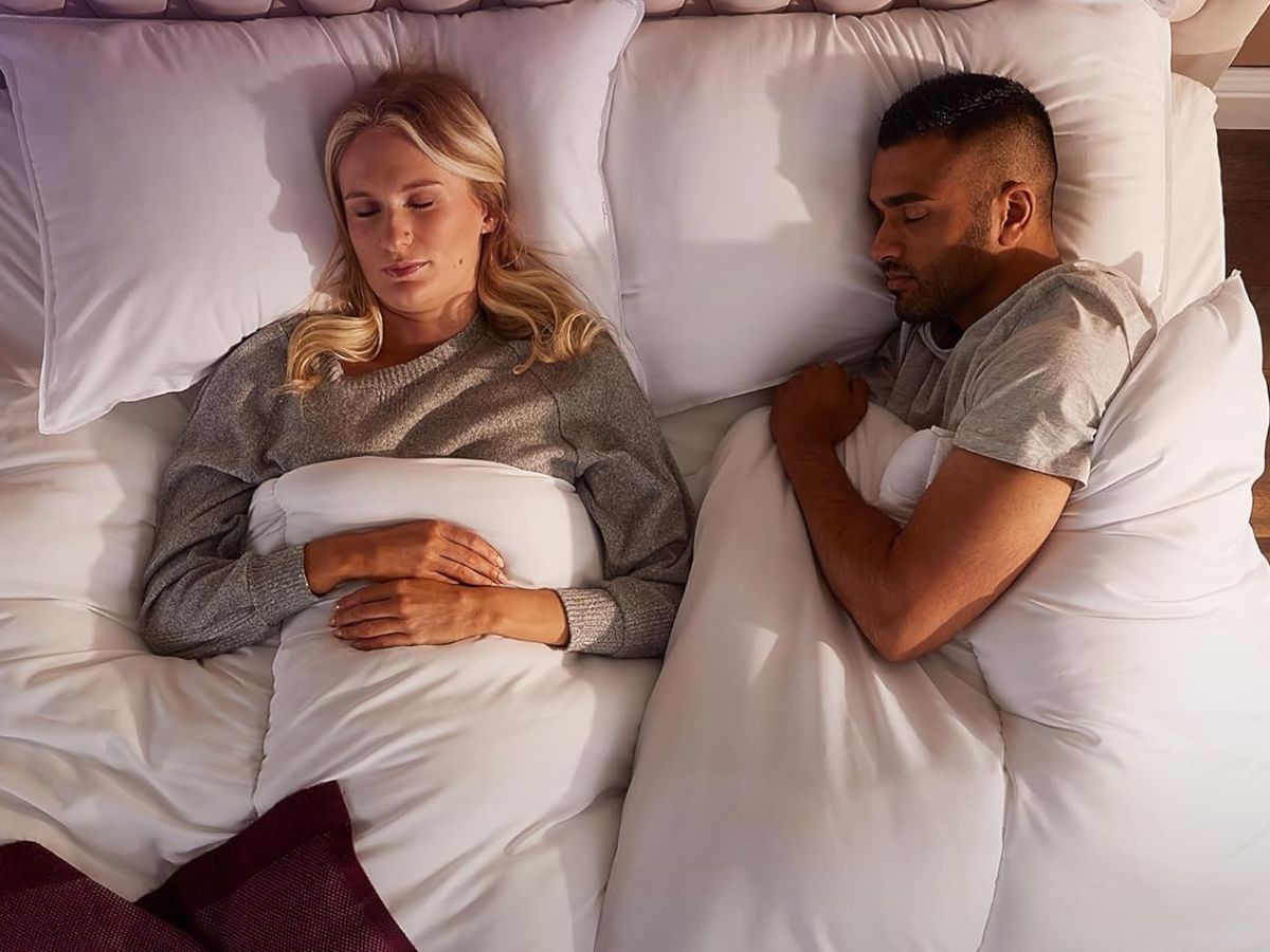 A man and woman sleeping in separate beds next to each other.