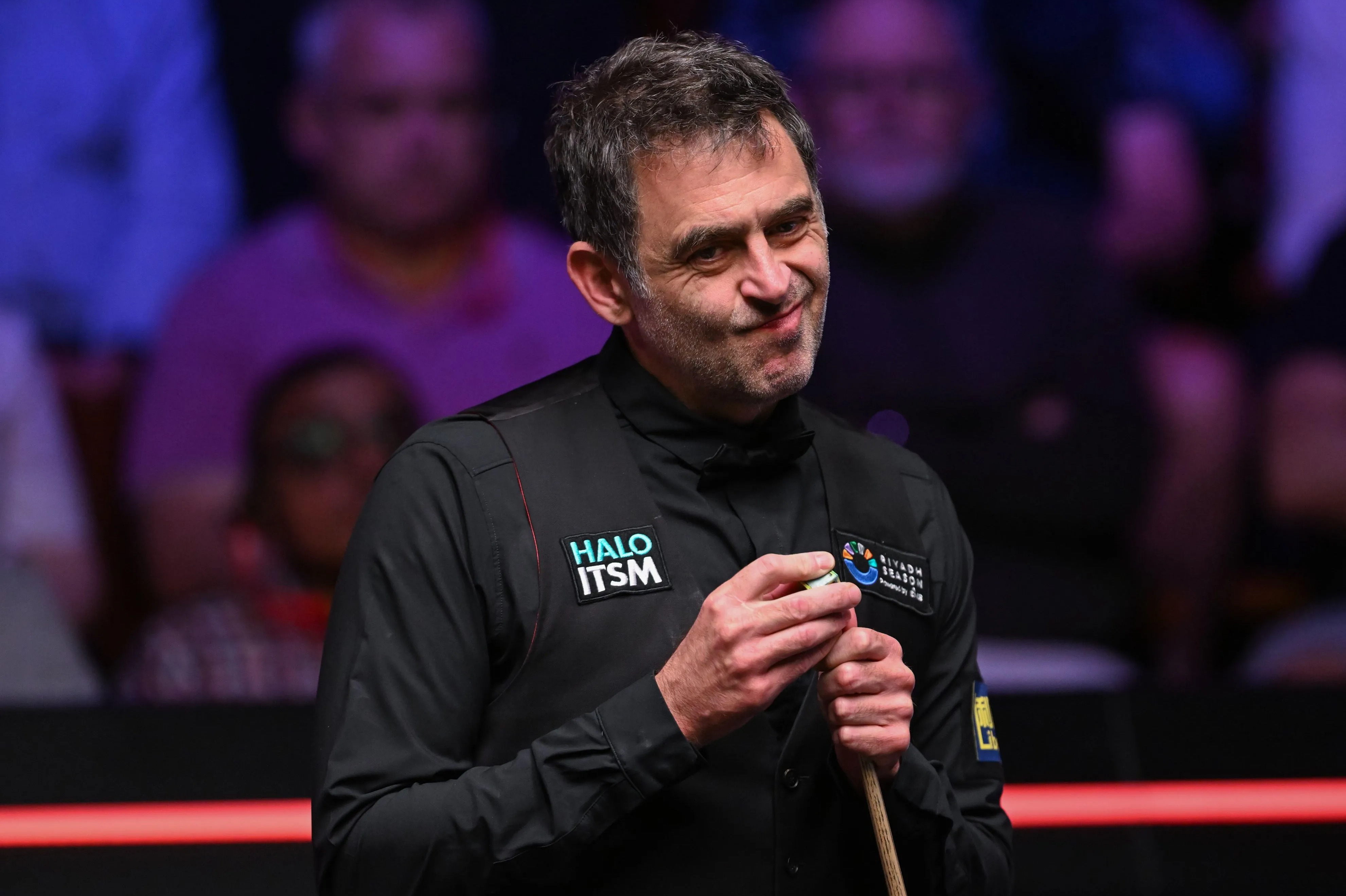 Ronnie O'Sullivan chalking his cue during a snooker match.