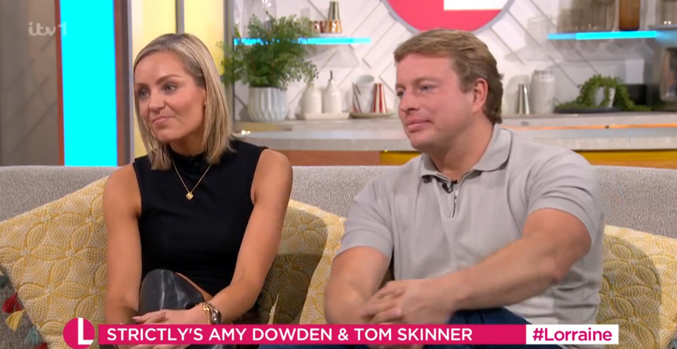 Amy Dowden and Tom Skinner sitting on a couch.