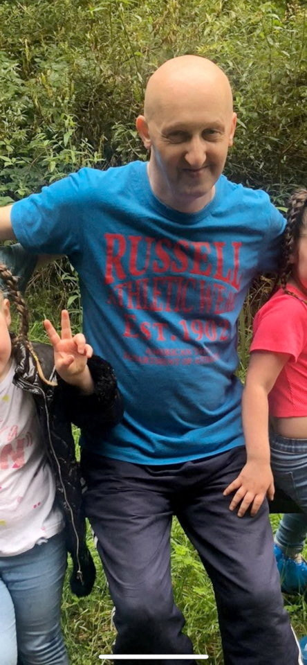 Adrian Daulby, a bald man in a blue Russell Athletic shirt, smiles at the camera.