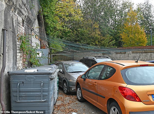 Cars parked behind Neil's workshop in Portsmouth under a sheet of protective netting