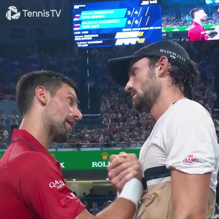 Tennis players Valentin Vacherot and Novak Djokovic shaking hands on the court after Vacherot defeated Djokovic.