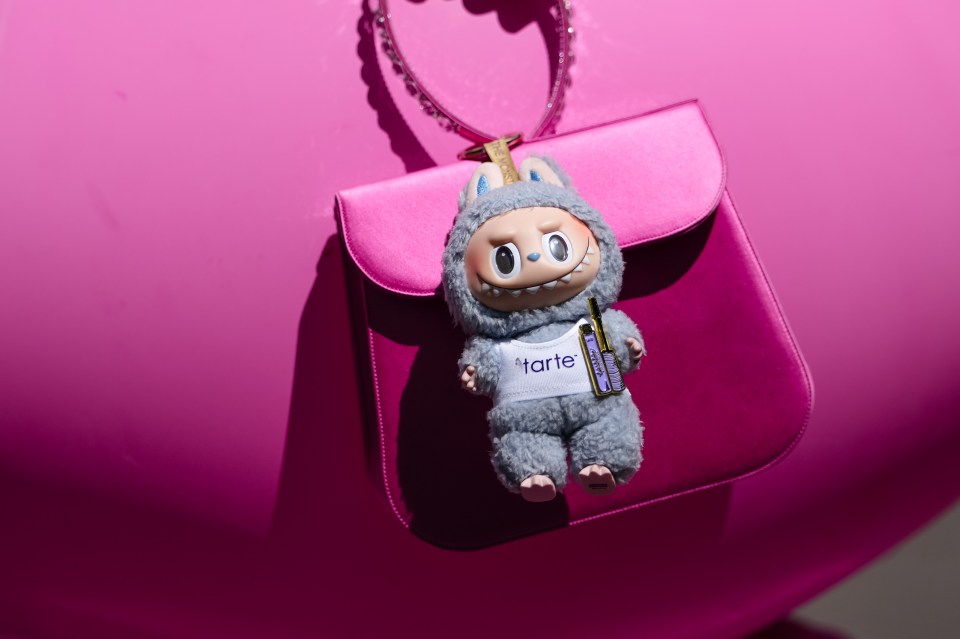 Close-up of a Labubu toy hanging on a bright pink purse.
