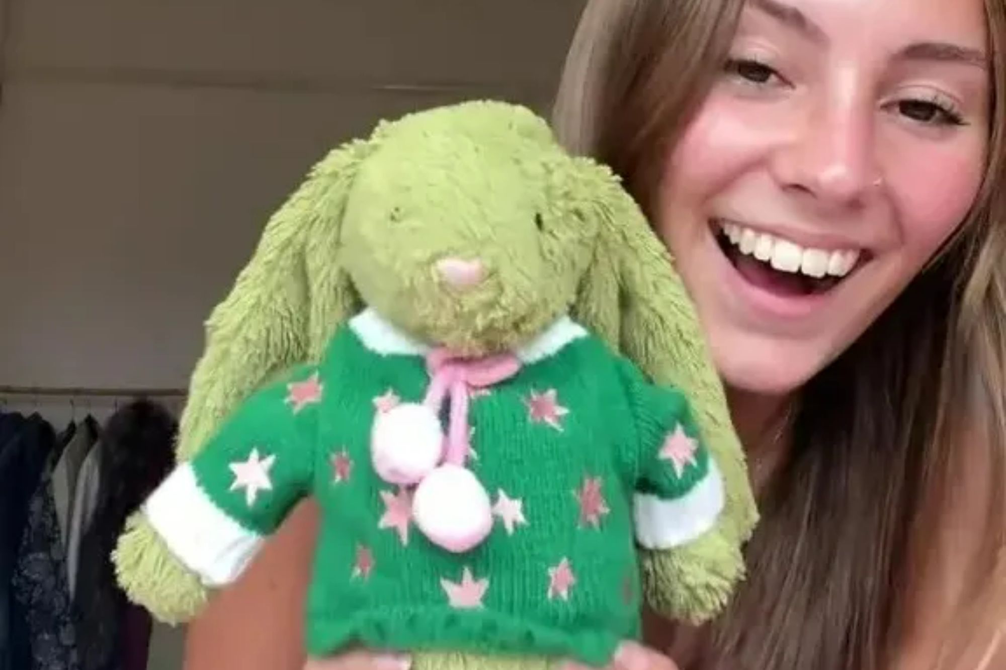 An image collage containing 1 images, Image 1 shows A person holding a green stuffed bunny wearing a green sweater with pink stars