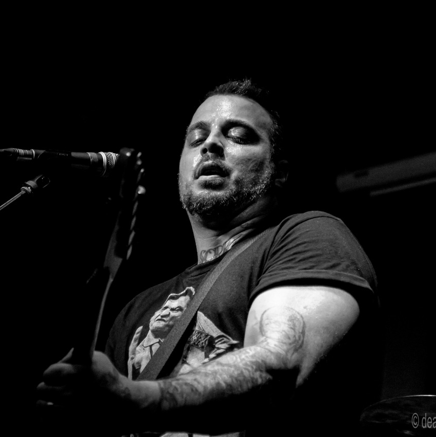 Headshot of RM Scott, a man with a beard and tattoos wearing a fedora.