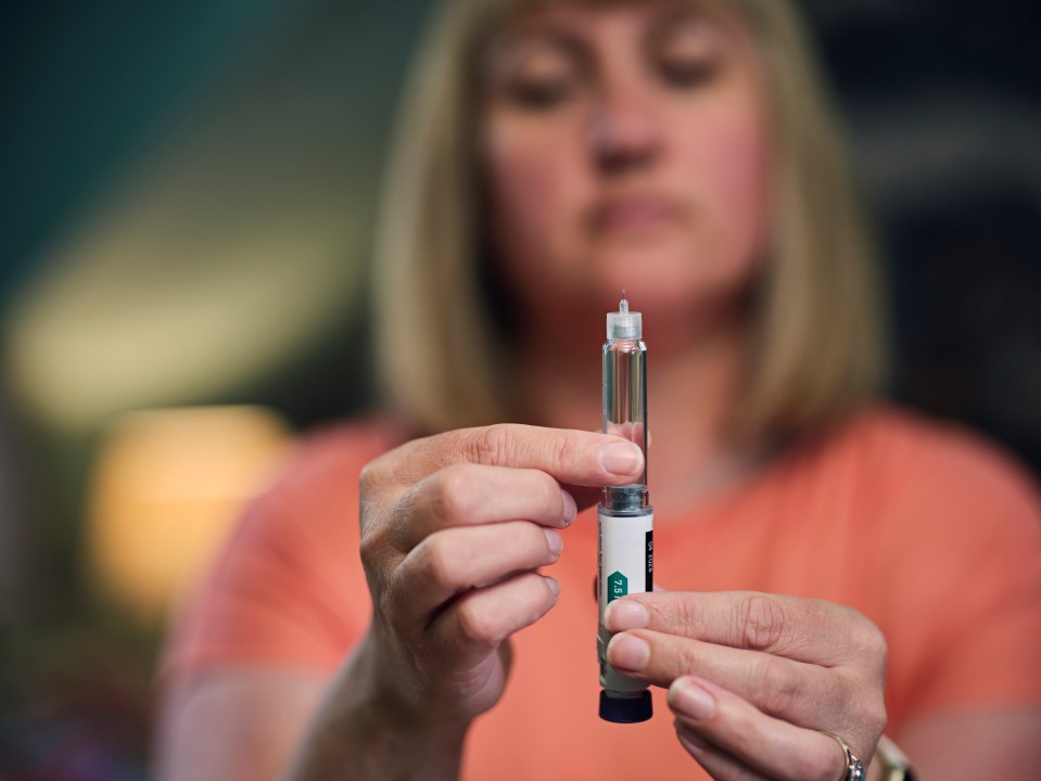 Woman preparing an injection pen for a medical dose.