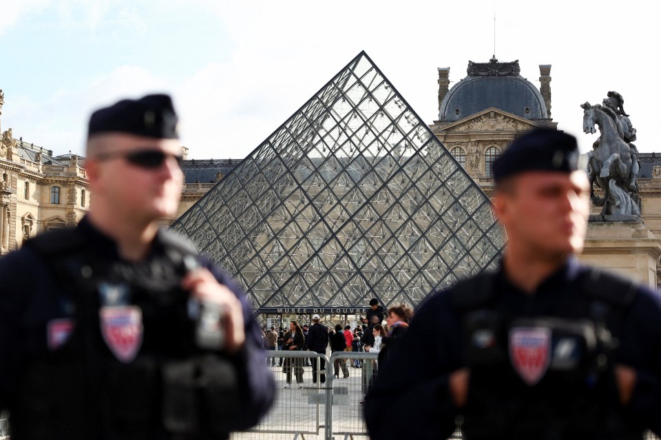 French CRS riot police stand near the glass Pyramid of the Louvre Museum