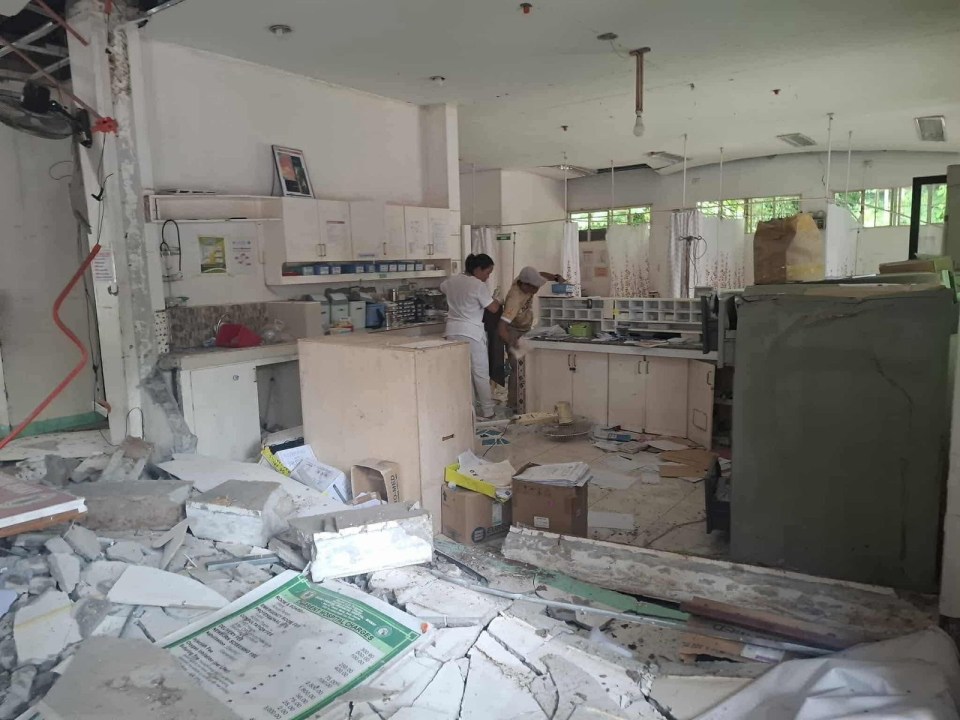 Two people in a government building littered with debris after an earthquake.