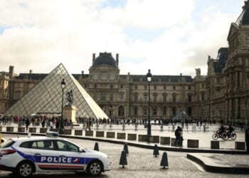 A police car parks in the courtyard of the Louvre museum in Paris, one week after the robbery on Sunday.