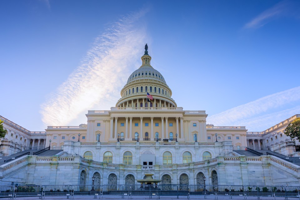 East side of the US Capitol Building with its grand neoclassical architecture and dome against a clear blue sky.