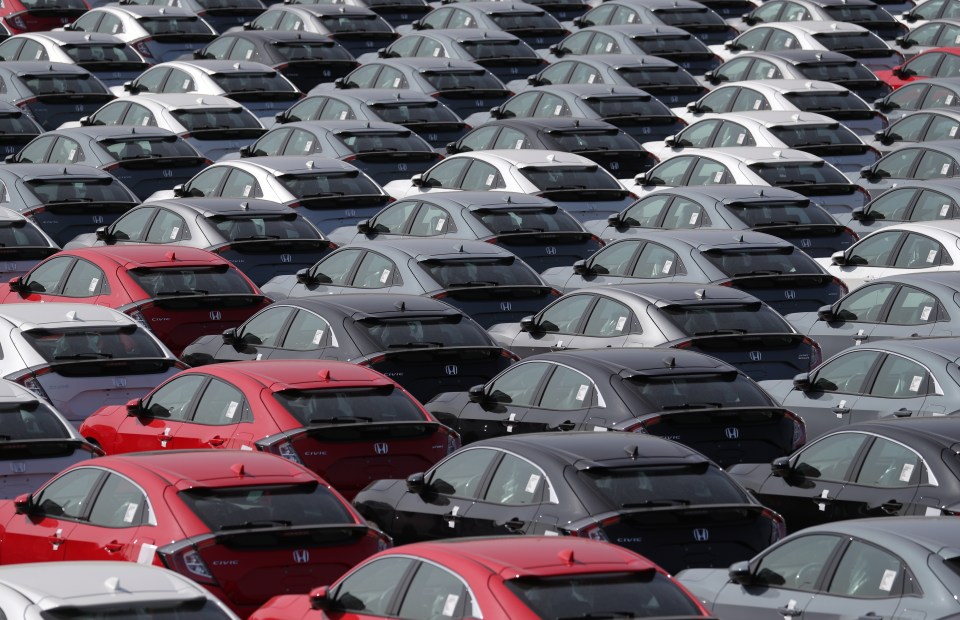 Rows of parked Honda Civic cars, predominantly gray, black, and white, with some red cars visible.