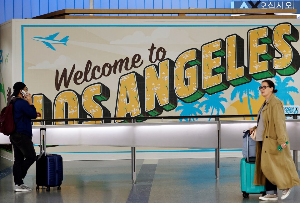 Travelers near a "Welcome to Los Angeles" sign in the international terminal at Los Angeles International Airport.