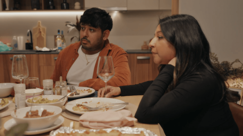 Steven and Nelly's sister sitting at a table with plates of food.